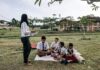 Limitless vs Limited Students in uniforms enjoying an outdoor class with a teacher in a park setting.